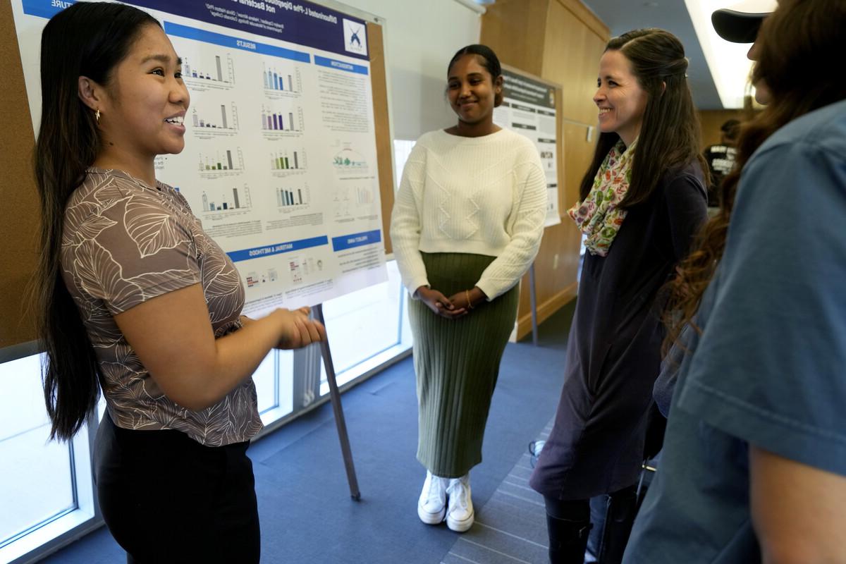 Student presenting their research on a poster board for onlookers